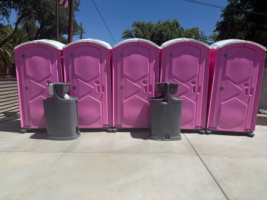 Row of pink porta potties with two handwashing stations for an event