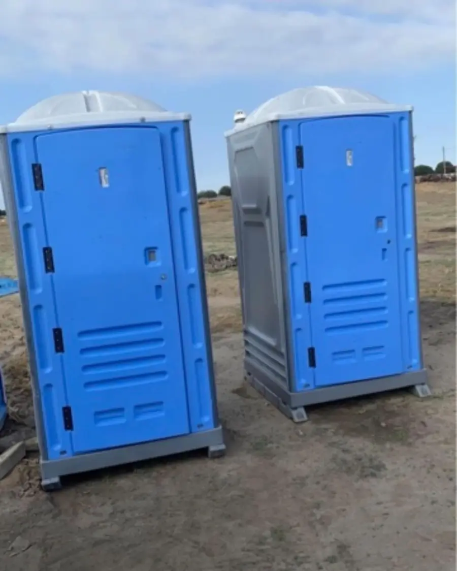 Blue and gray porta potties set on a dirt construction lot