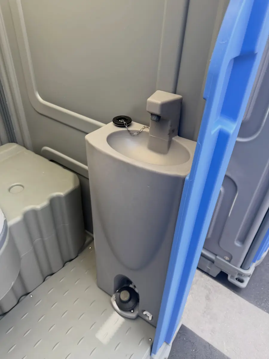 Porta potty interior with built-in hand-wash sink and soap
